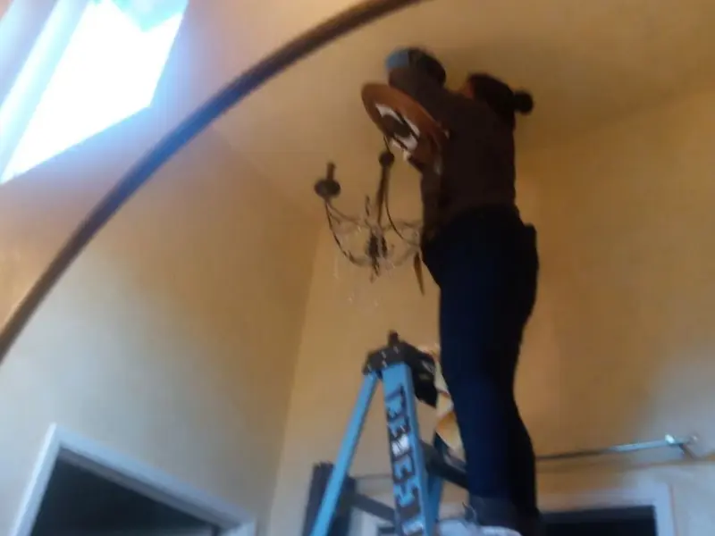 Electrician installing a chandelier in a Wyboo residence